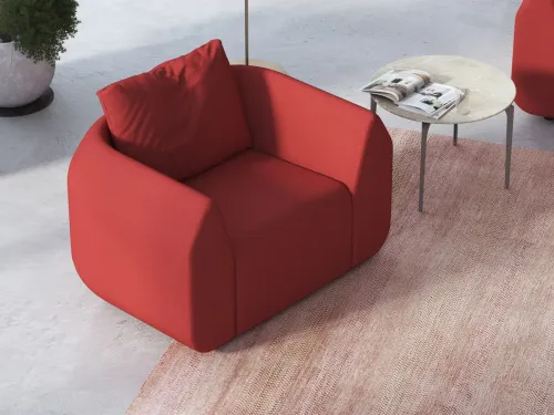 Ark kırmızı tekli koltuk, kavisli ve sarıcı formuyla yönetici bekleme alanları, lobi ve marka lounge alanlarında heykelsi bir oturma etkisi oluşturur.
