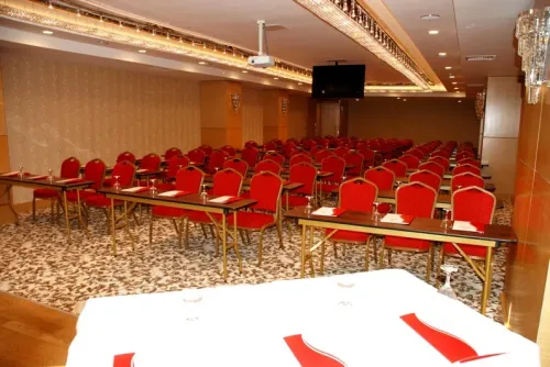 Kırmızı sandalyeler, sıralı masa düzeni ve geniş salon kurgusuyla seminer alanı, eğitim ve kurumsal organizasyonlara uygun bir yapı taşır.