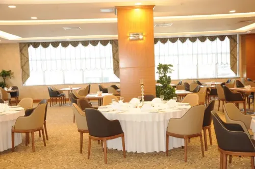 Divalin Hotel projesinde restoran ve banket alanı, yuvarlak masa düzeni ve sıcak otel atmosferiyle davet ve yemek organizasyonlarına uygun bir mekân sunar.