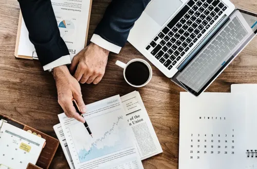 Dizüstü bilgisayar, raporlar, takvim ve grafiklerle hazırlanmış çalışma masası, etkili toplantı yönetimi ve verimli karar alma süreçlerini anlatan profesyonel bir ofis blog görseli.
