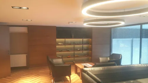 Siyah deri koltuklar, yuvarlak tavan aydınlatmaları ve ahşap yüzeylerle hazırlanan lounge alanı, yönetici ofisine sıcak ve prestijli bir karakter kazandırır.