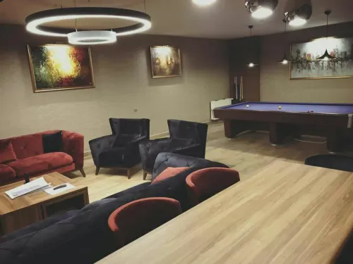 Bilardo alanı, siyah ve bordo oturma öğeleri ve sıcak aydınlatma diliyle ofis içinde temsil ve dinlenme odaklı özel bir atmosfer oluşturur.