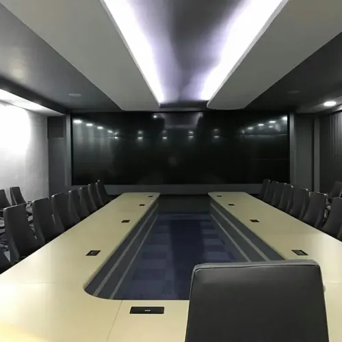 Malatya Büyükşehir Belediyesi AYKOME Şube Müdürlüğü projesinde geniş toplantı masası, koyu panel duvar ve gri ofis koltuklarıyla kurumsal bir toplantı alanı oluşturulur.