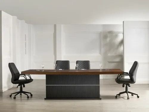 Omnia toplantı masası, ceviz yüzeyi, koyu lamel panel etkisi ve premium yönetici odası diliyle modern makam takımının toplantı alanına uzanan güçlü devamını sunar.