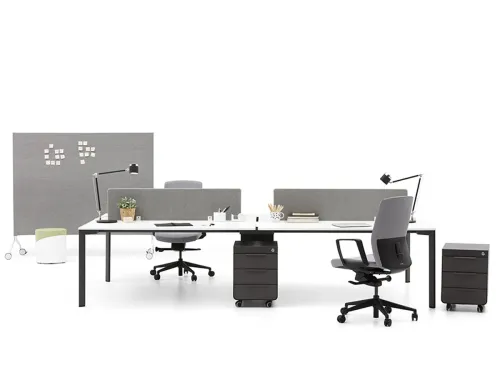 PUZZLE ikili workstation, beyaz çalışma yüzeyi, gri panel bölücüleri ve koyu metal ayaklarıyla açık ofislerde net bir çalışma alanı oluşturur.
