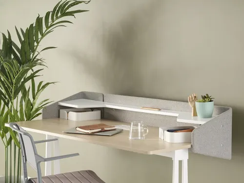 Runner Home’un açık ahşap yüzeyi, üst raf sistemi ve yumuşak keçe paneli, ev içinde daha samimi tasarımlı bir çalışma masası atmosferi oluşturur.